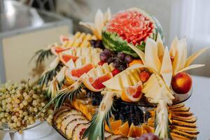 un banquete mesa lleno de frutas y bayas, un surtido de dulces plátanos, uvas, piñas. Fruta composiciones para el día festivo. foto