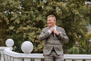 Portrait of a handsome young groom on an autumn day outdoors in an elegant suit. Outdoor photo. Handsome man in a business suit. photo