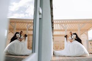 A handsome groom embraces his beloved in a beautiful location. Reflection in the mirror of the bride and groom. Wide format photo. photo