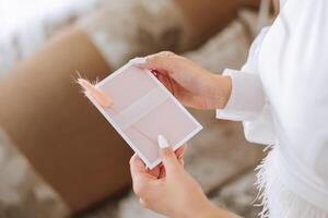 The bride in her hands holds a white envelope, an invitation, a gift sheet of paper. Close-up wedding photography, copy space, portrait. photo