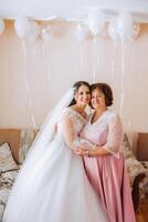 A beautiful and happy mother and her daughter, the bride, are standing next to each other. The best day for parents. Tender moments at the wedding. photo