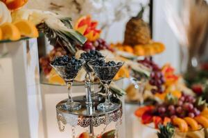 A banquet table full of fruits and berries, an assortment of sweets. Bananas, grapes, pineapples. Fruit compositions for the holiday. photo