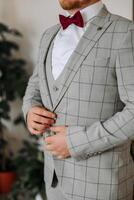 the groom's hands fasten his jacket in the morning before the wedding. close-up of a man in business suit. Businessman puts on a suit. The man fastens the buttons on his jacket. photo