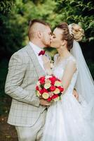 A young bride and groom tenderly embrace in the rays of the autumn sun. Tender and beautiful young girl bride. A man kisses his beloved. Against the background of a beautiful garden photo