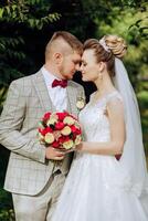 A young bride and groom tenderly embrace in the rays of the autumn sun. Tender and beautiful young girl bride. A man kisses his beloved. Against the background of a beautiful garden photo