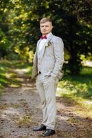 Portrait of a handsome young groom on an autumn day outdoors in an elegant suit. Outdoor photo. Handsome man in a business suit. photo