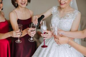 foto con damas de honor Bebiendo champán desde lentes en el Mañana en un hermosa hotel. foto de un hermosa joven novia y su amigos en pareo vestidos Bebiendo champán antes de el boda.