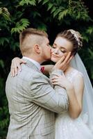 un joven novia y novio tiernamente abrazo en el rayos de el otoño Dom. oferta y hermosa joven niña novia. un hombre Besos su amado. en contra el antecedentes de un hermosa jardín foto