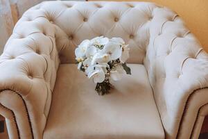 Wedding bouquet. Freshly cut roses, green seed heads and leaves. Green stems, white ribbon and gold wedding rings. The concept of a wedding bouquet. photo