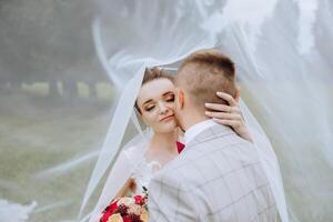 A young bride and groom tenderly embrace in the rays of the autumn sun. Tender and beautiful young girl bride. A man kisses his beloved. Against the background of a beautiful garden photo