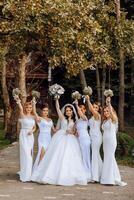 Wedding photography. A brunette bride in a white dress with a bouquet and her brunette girlfriends photo