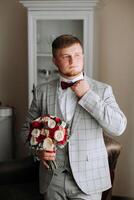 novio con un ramo de flores de rosas, novio con ramo, novio con un Boda ramo, un joven hombre con un Boda ramo de flores en su mano, bien adecuado hombre foto