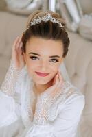 portrait of an incredibly beautiful girl bride in a white robe in the bedroom, the bride poses in the morning before the wedding ceremony. photo