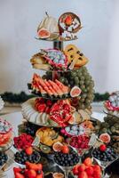 A banquet table full of fruits and berries, an assortment of sweets. Bananas, grapes, pineapples. Fruit compositions for the holiday. photo