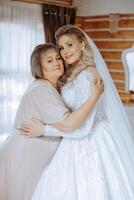 A beautiful and happy mother and her daughter, the bride, are standing next to each other. The best day for parents. Tender moments at the wedding. photo