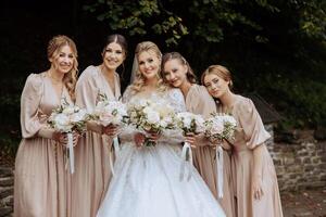 Wedding photography. A brunette bride in a white dress with a bouquet and her brunette girlfriends photo