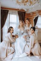 Portrait of the bride with her friends. Elegant and stylish bride with her friends in matching dresses in the room in the morning. Many beautiful girls in one photo. photo