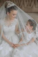 Portrait of the bride with her little sister in the room. Tender and sweet photo of a beautiful bride with her little sister.