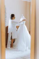 Morning preparation of an incredibly beautiful bride. A girl in a beautiful robe near a wedding dress standing on a mannequin indoors. Wedding preparations of the bride. photo