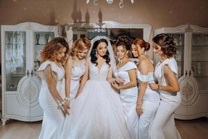 Portrait of the bride with her friends. Elegant and stylish bride with her friends in matching dresses in the room in the morning. Many beautiful girls in one photo. photo