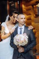 lovely and stylish newlyweds are hugging and smiling against the background of autumn nature in a beautiful garden. An incredibly beautiful young bride leaned against the shoulder of her beloved groom photo