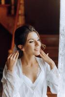 portrait of an incredibly beautiful girl bride in a white robe in the bedroom, the bride poses in the morning before the wedding ceremony. photo