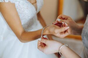 Wedding bride and bridesmaid help with jewellery bracelet for elegant and classic fashion glamour. Expensive bridal diamond accessory for classy style at special ceremony event day closeup. photo