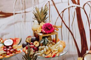 un banquete mesa lleno de frutas y bayas, un surtido de dulces plátanos, uvas, piñas. Fruta composiciones para el día festivo. foto