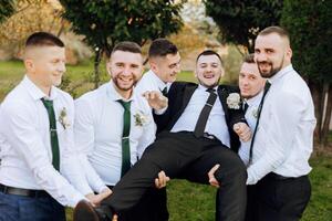 Boda foto sesión en naturaleza. amigos sostener el novio en su brazos