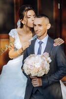 lovely and stylish newlyweds are hugging and smiling against the background of autumn nature in a beautiful garden. An incredibly beautiful young bride leaned against the shoulder of her beloved groom photo