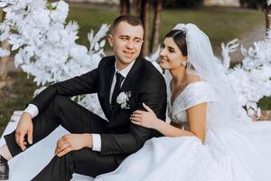 lovely and stylish newlyweds are hugging and smiling against the background of autumn nature in a beautiful garden. An incredibly beautiful young bride leaned against the shoulder of her beloved groom photo