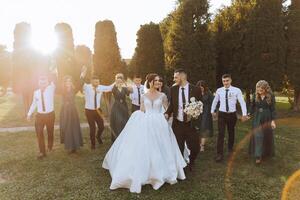 Wedding photo session in nature. The bride and groom kiss and their friends