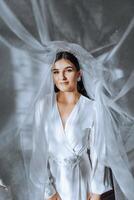 portrait of an incredibly beautiful girl bride in a white robe in the bedroom, the bride poses in the morning before the wedding ceremony. photo