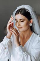 portrait of an incredibly beautiful girl bride in a white robe in the bedroom, the bride poses in the morning before the wedding ceremony. photo