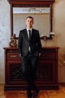 Portrait of smiling successful Caucasian man in formal suit, posing in room, happy young male boss or CEO looking at camera, showing confidence and strength, leadership concept photo