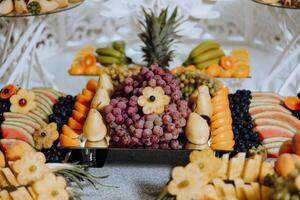 un banquete mesa lleno de frutas y bayas, un surtido de dulces plátanos, uvas, piñas. Fruta composiciones para el día festivo. foto