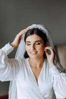 portrait of an incredibly beautiful girl bride in a white robe in the bedroom, the bride poses in the morning before the wedding ceremony. photo