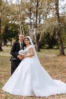 Wedding couple on a walk in the autumn park. The bride in a beautiful white dress. Love and relationship concept. Groom and bride in nature outdoors photo