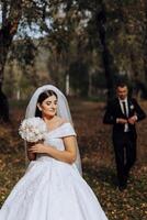 Wedding couple on a walk in the autumn park. The bride in a beautiful white dress. Love and relationship concept. Groom and bride in nature outdoors photo