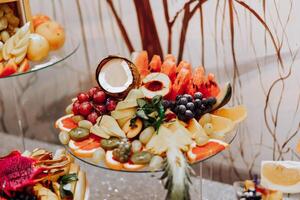 A banquet table full of fruits and berries, an assortment of sweets. Bananas, grapes, pineapples. Fruit compositions for the holiday. photo