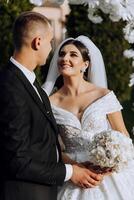 A young bride and groom tenderly embrace in the rays of the autumn sun. Tender and beautiful young girl bride. A man kisses his beloved. Against the background of a beautiful garden photo