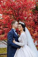 un joven novia y novio tiernamente abrazo en el rayos de el otoño Dom. oferta y hermosa joven niña novia. un hombre Besos su amado. en contra el antecedentes de un hermosa jardín foto