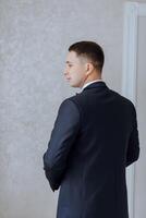 Back portrait of successful Caucasian man in formal suit, posing in room, happy young male boss or CEO, showing confidence and strength, leadership concept photo