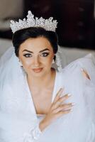 portrait of an incredibly beautiful girl bride in a white robe in the bedroom, the bride poses in the morning before the wedding ceremony. photo