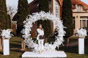 A female master of ceremonies is dressed in a white suit, during a speech. photo