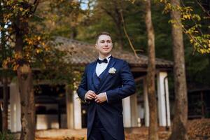 Portrait of a handsome young groom on an autumn day outdoors in an elegant suit. Outdoor photo. Handsome man in a business suit. photo