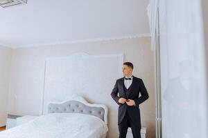 young smiling man buttoning up his jacket in the morning before the wedding. close-up of a man in a business suit. Businessman puts on a suit. A man fastens the buttons on his jacket. photo