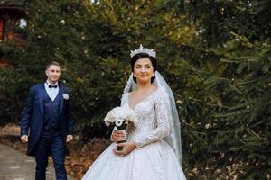Wedding couple on a walk in the autumn park. The bride in a beautiful white dress. Love and relationship concept. Groom and bride in nature outdoors photo