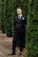 retrato de un hermoso joven novio en un otoño día al aire libre en un elegante traje. al aire libre foto. hermoso hombre en un negocio traje. foto