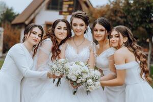 Wedding photography. A brunette bride in a white dress with a bouquet and her brunette girlfriends photo